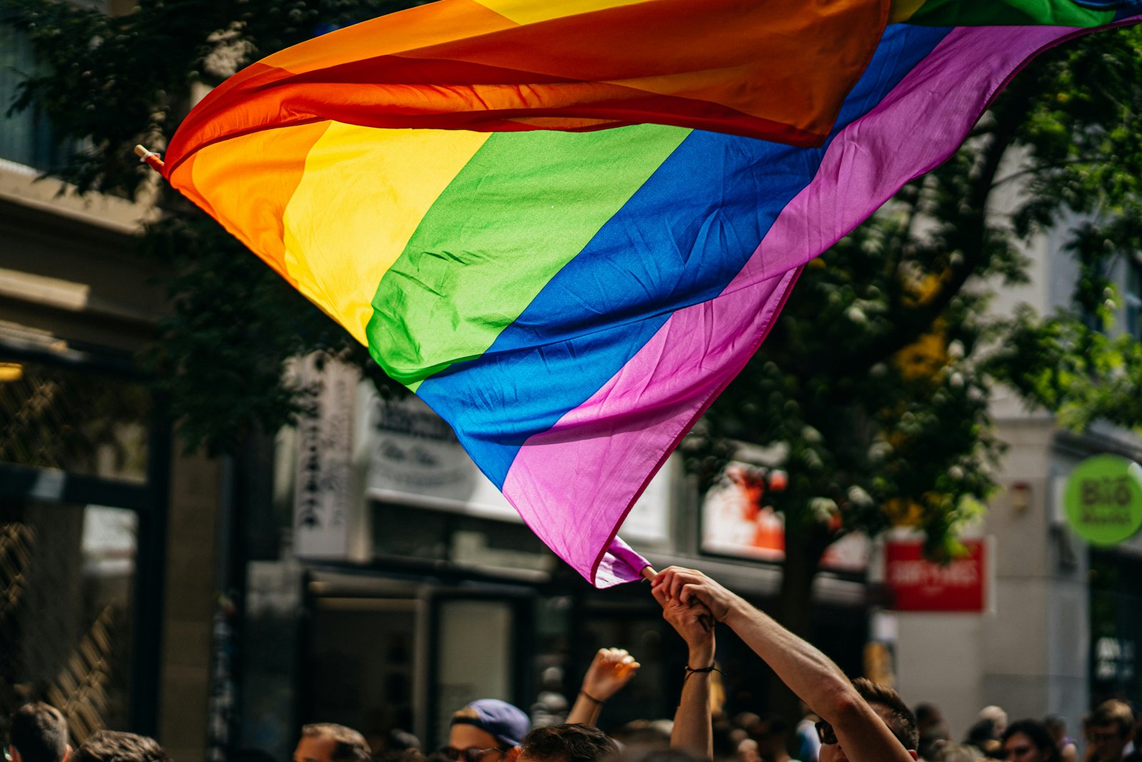 A person waving a rainbow Pride flag at a Pride festival