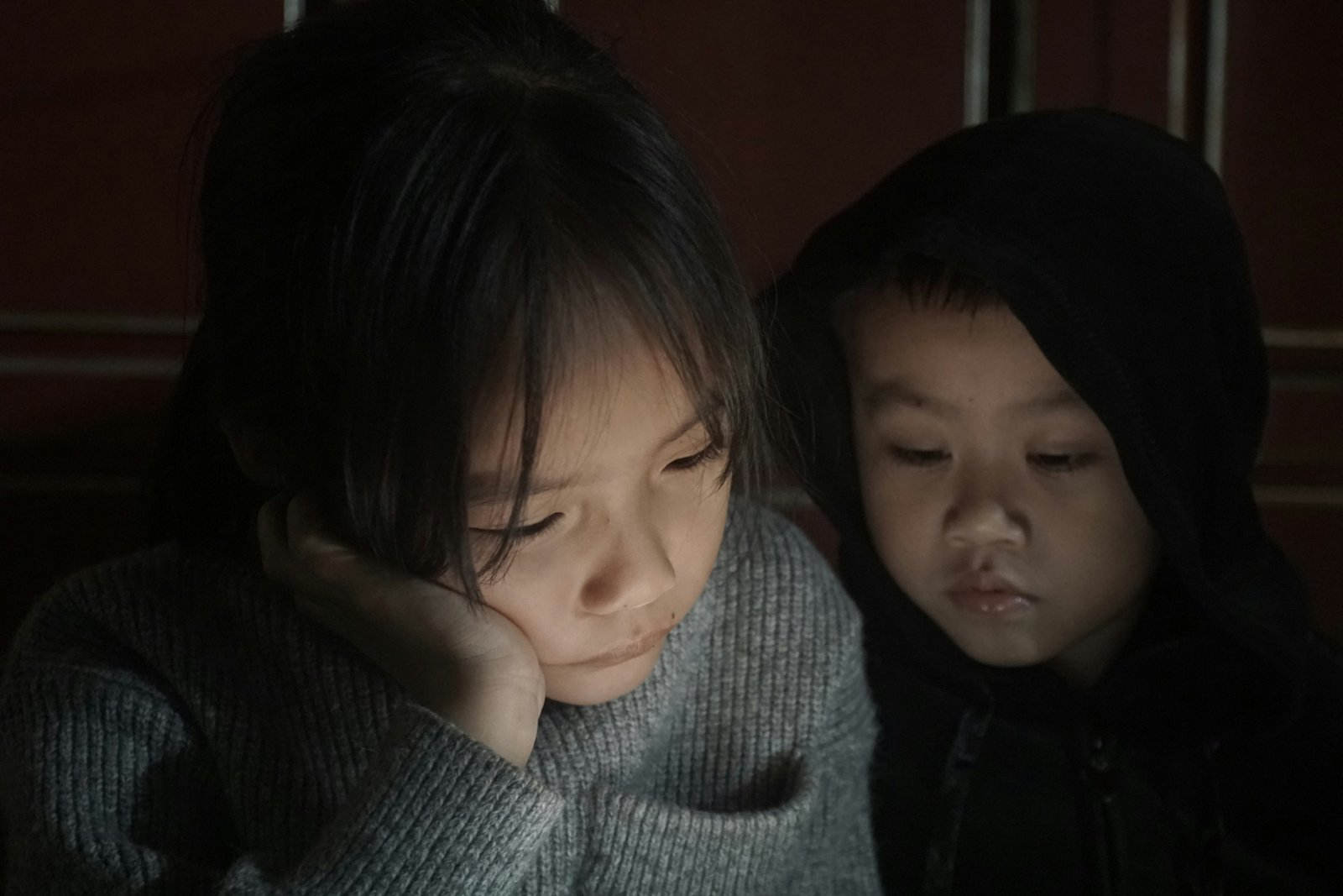Two young children sitting close together, looking down